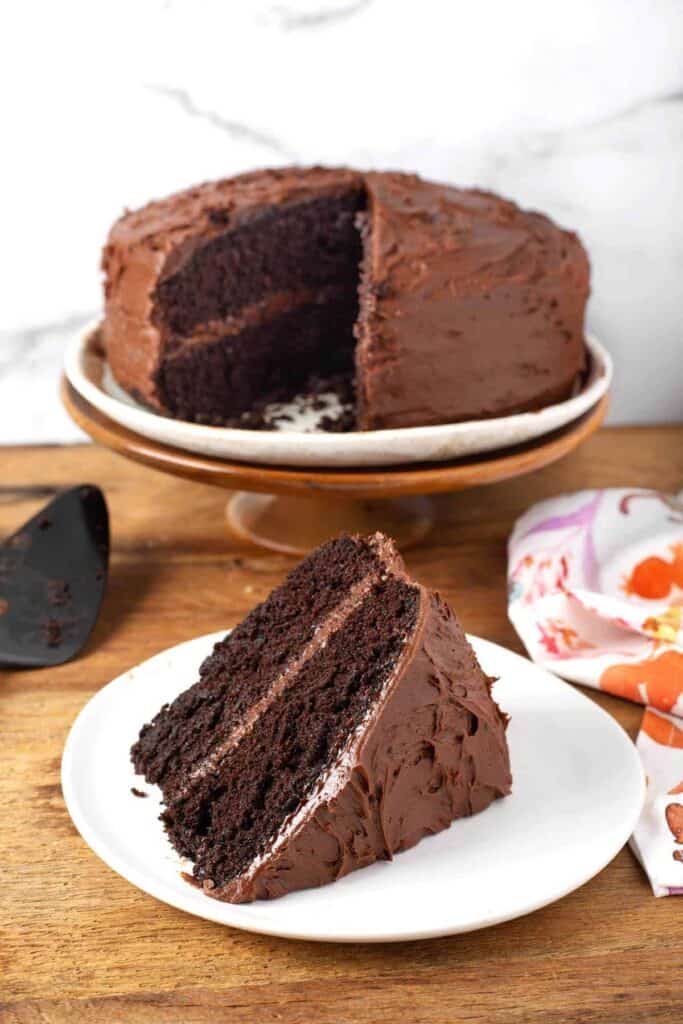 Chocolate Mayonnaise Cake on a stand with a piece on a white plate
