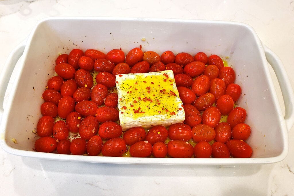 white baking dish with feta in the middle with spices
