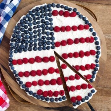 Patriotic Fruit Pizza with frosting, blueberries and raspberries on a wood background