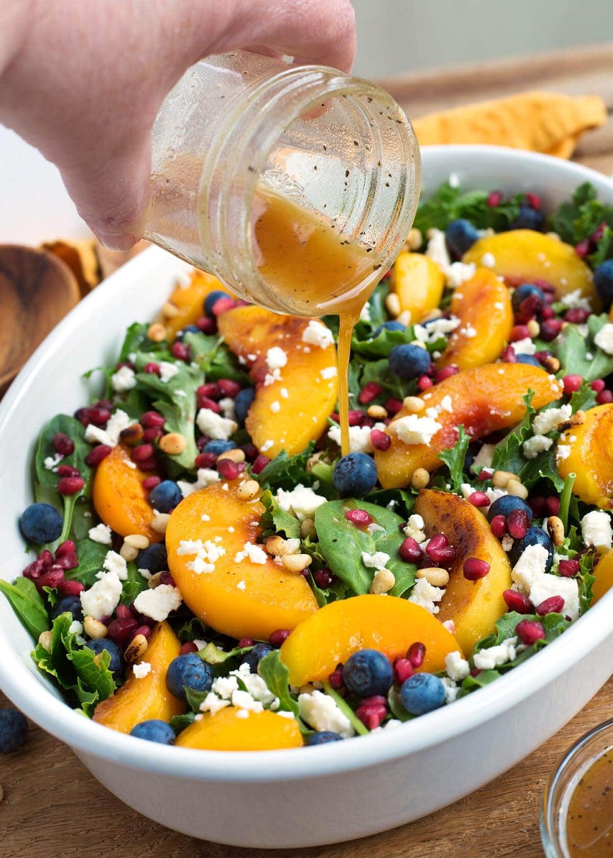 Peach Salad in a white oval dish with hand pouring dressing on it