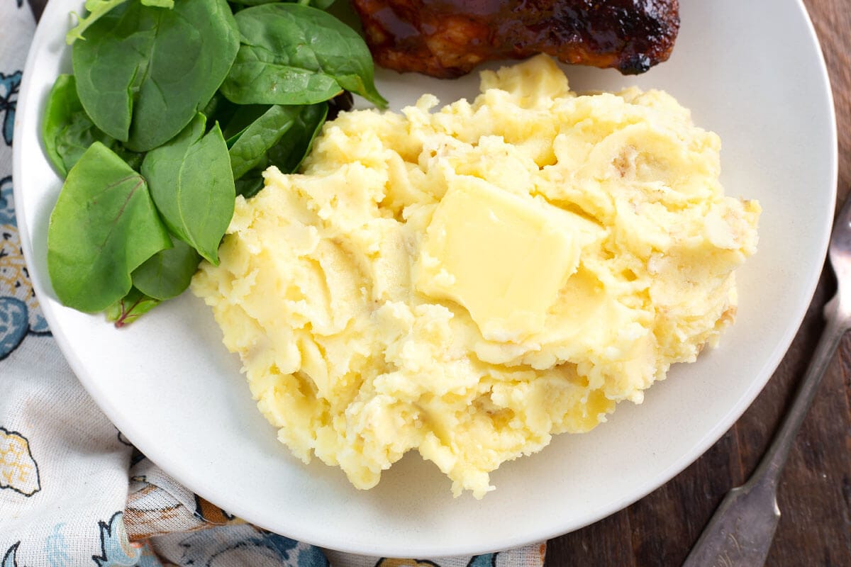 Mashed Potatoes on a white plate with butter on them