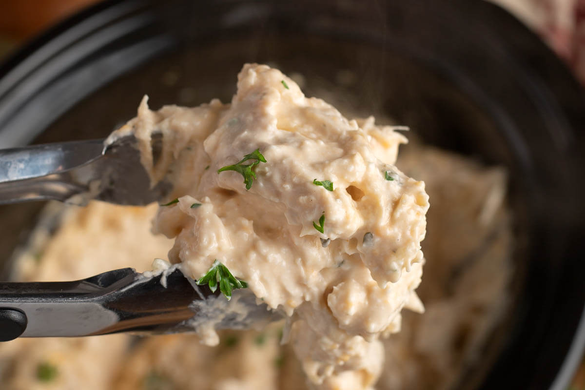 Slow Cooker Creamy Ranch Chicken in tongs