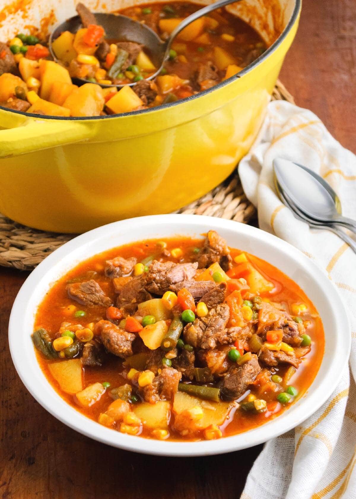Homestyle Vegetable Beef Soup in a white bowl and yellow pot