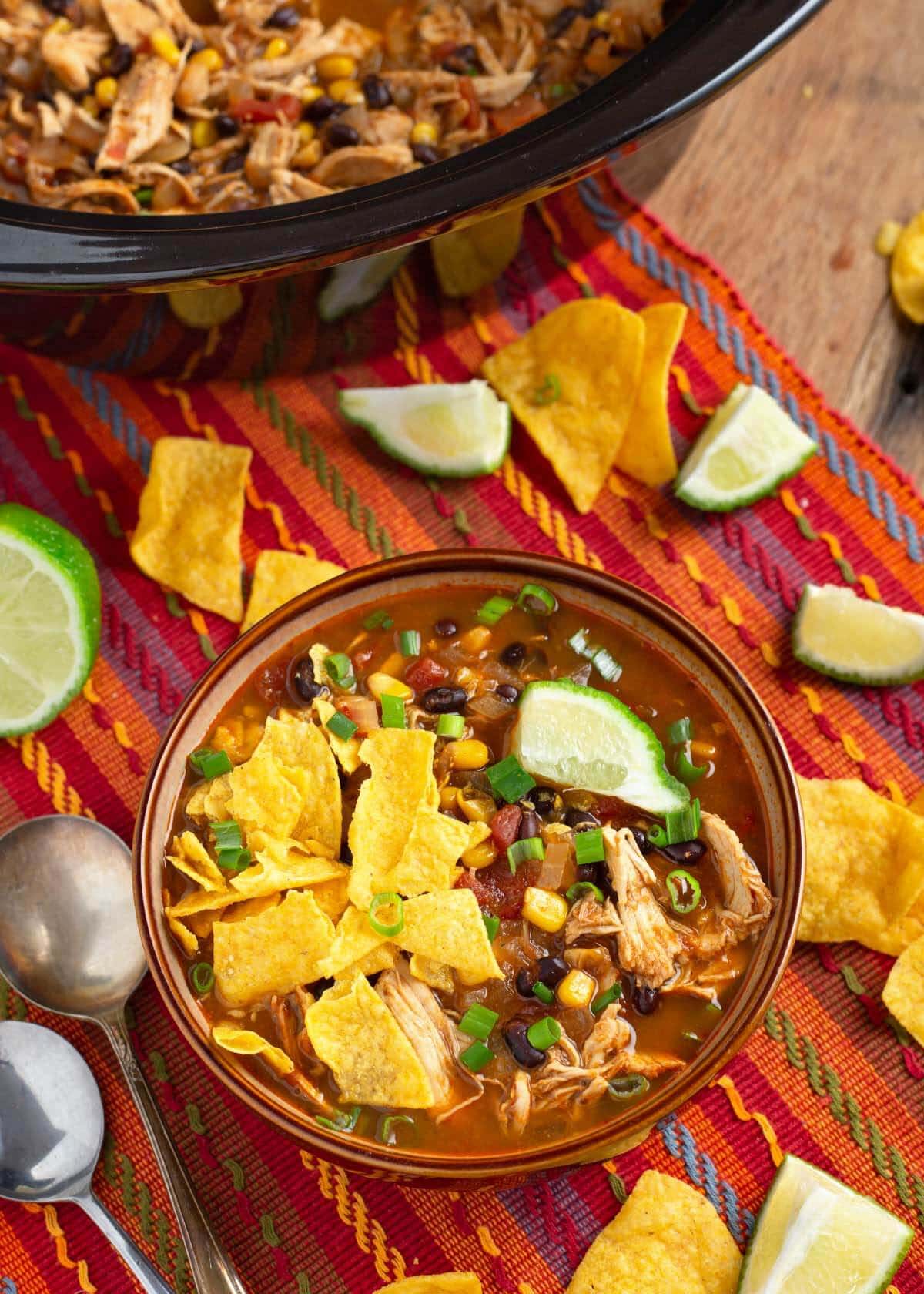 Chicken Tortilla Soup in a brown bowl in front of slow cooker