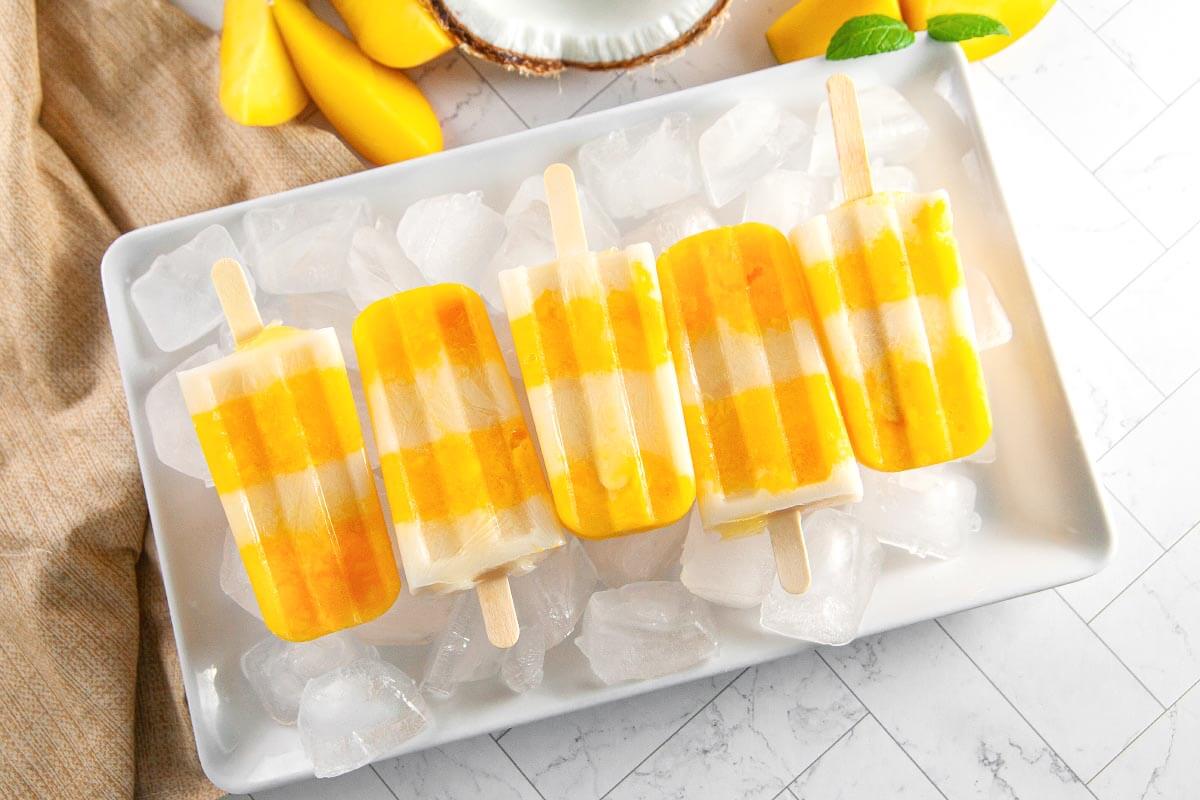 Mango Popsicles on a white tray. 3 Fun Summer Desserts.
