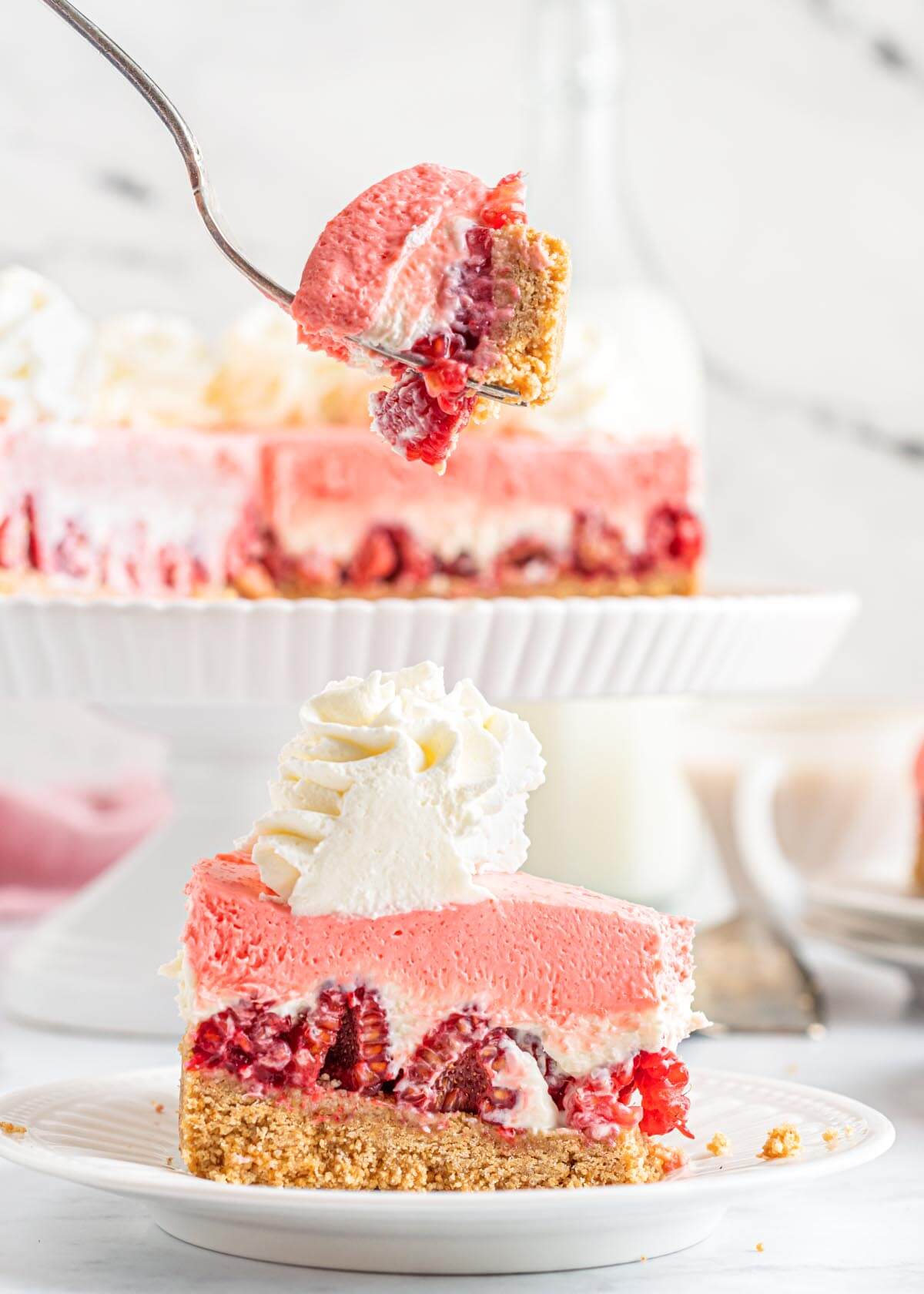 slice of raspberry cheesecake on a plate and bite on a fork.