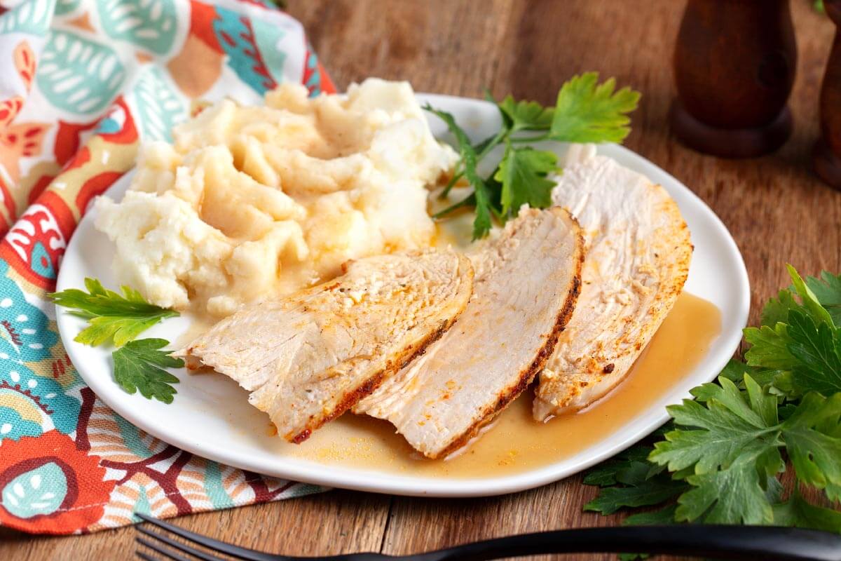 Chicken slices on a white plate with potatoes and gravy
