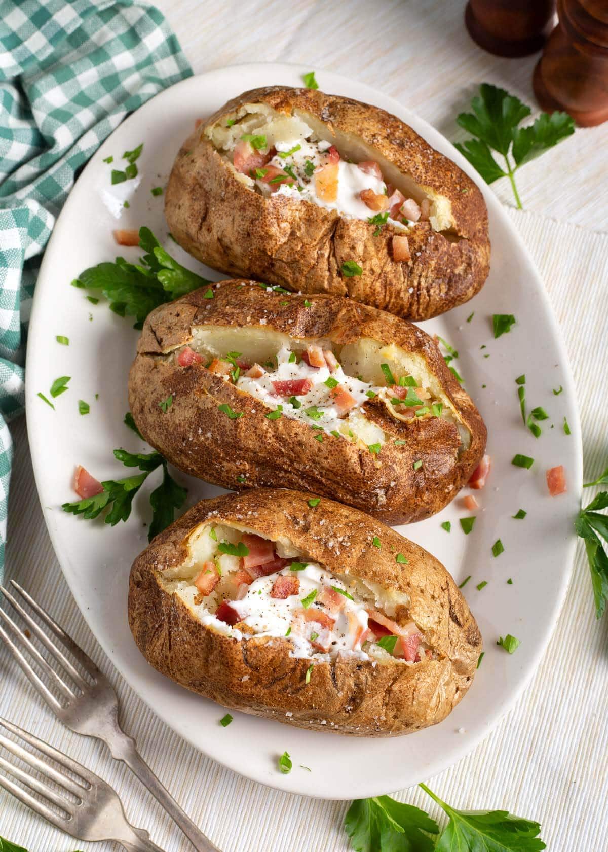 3 baked potatoes on a plate.