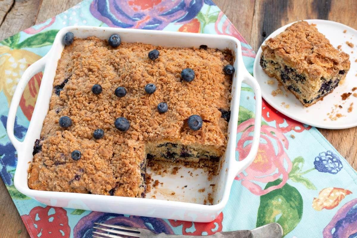Blueberry Coffee Cake - Blueberry Buckle in baking dish with slice on a plate.