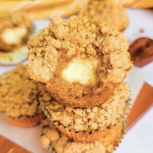 pumpkin cream cheese muffins stacked with bite from one.