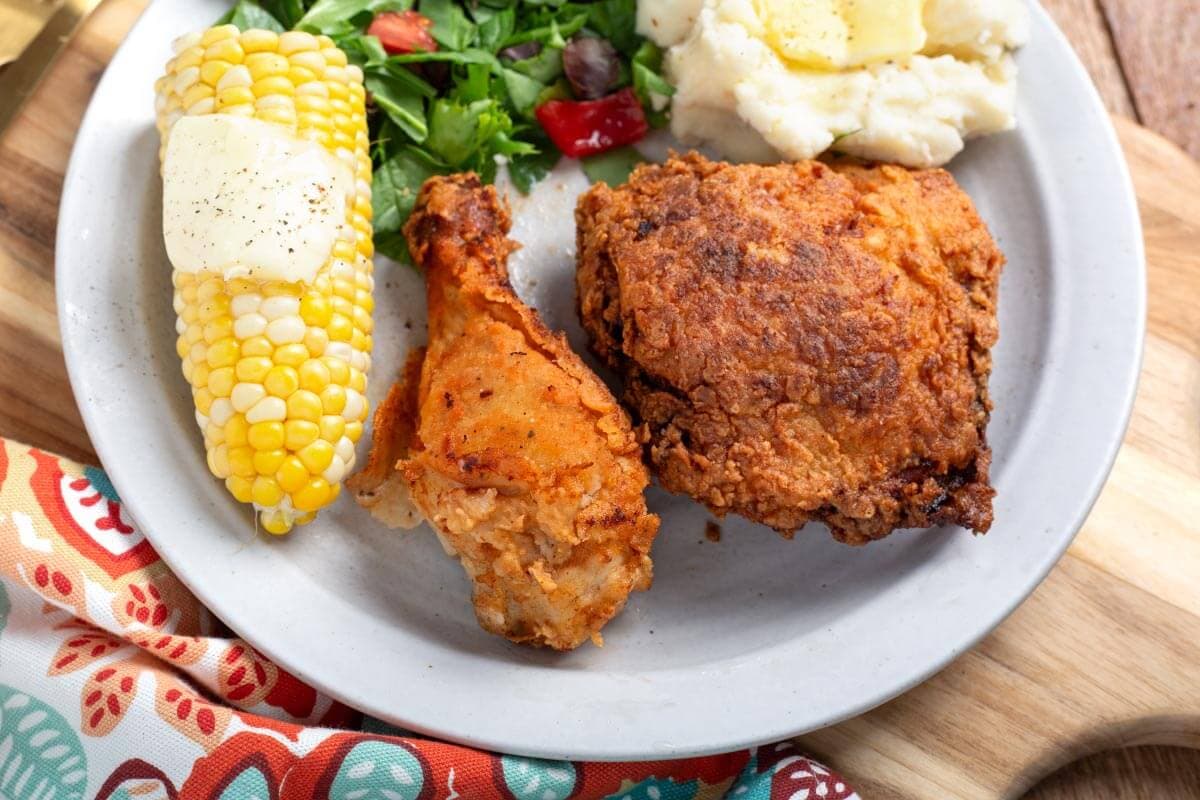 plate of 2 pieces fried chicken, corn cob, mashed potatoes.