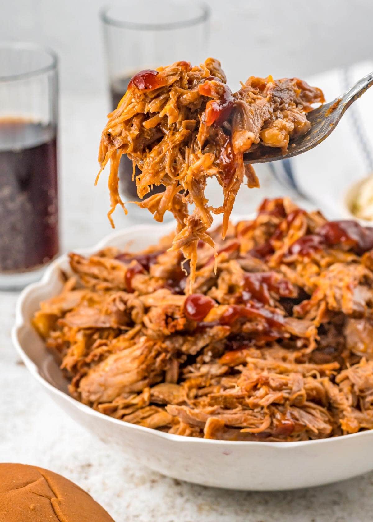 Slow Cooker Cherry Cola Pulled Pork in white dish with some on fork.