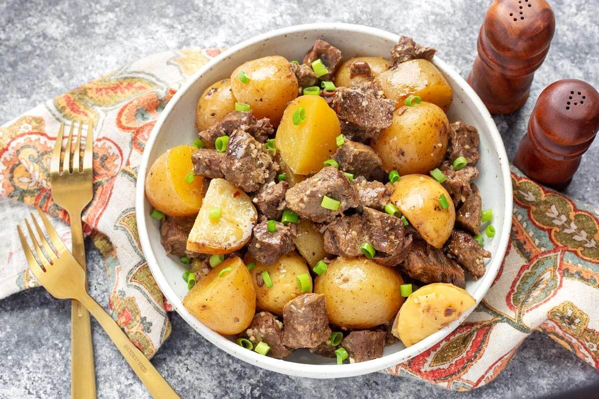 Slow Cooker Garlic Butter Steak Bites and Potatoes in a white bowl