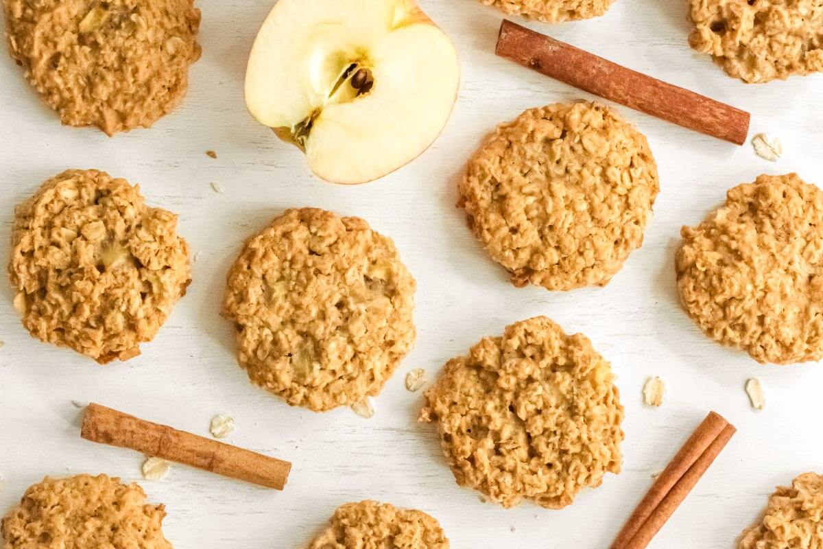 Apple Oatmeal Cookies on a white table with cinnamon sticks and apple